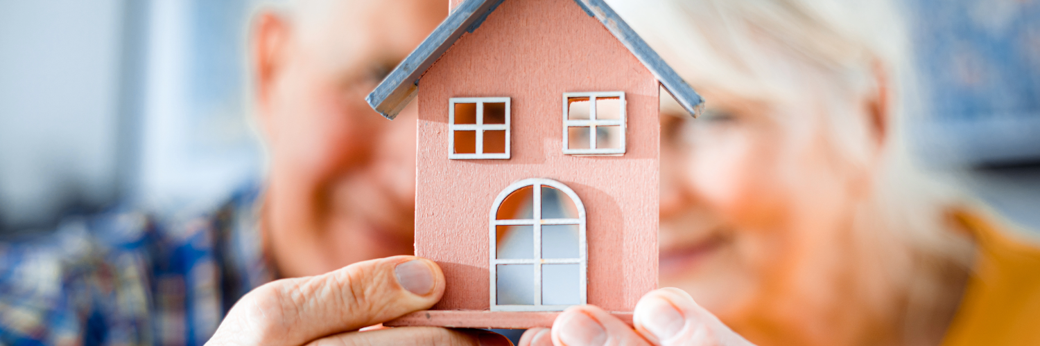 senior man and woman holding a house